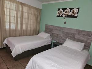 Postel nebo postele na pokoji v ubytování Rustenburg Palm Lodge
