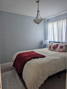 a bedroom with a bed with a red blanket and a window at The Love Love Stay in Edmonton