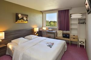 a hotel room with a bed and a desk and a window at Als Hôtel in Ottmarsheim
