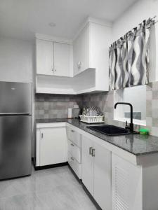 La cuisine est équipée de placards blancs et d'un réfrigérateur en acier inoxydable. dans l'établissement Kings' Palms Residence04, à General Santos