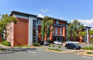 un bâtiment avec des voitures garées dans un parking dans l'établissement Road Lodge Centurion, à Centurion