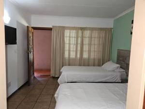 Postel nebo postele na pokoji v ubytování Rustenburg Palm Lodge