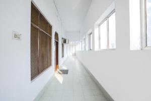 pasillo vacío con suelo de baldosa blanca y ventanas grandes en FabHotel Madhuri Annex, en Ayodhya
