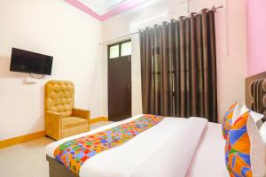 1 dormitorio con 1 cama, 1 silla y TV en FabHotel Madhuri Annex, en Ayodhya