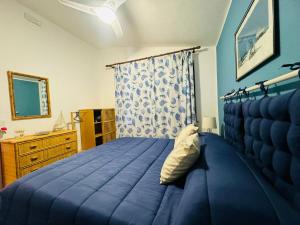 a bedroom with a blue bed and a dresser at La maison sul mare in San Vito lo Capo