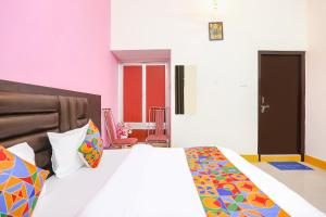 1 dormitorio con 1 cama grande y almohadas coloridas en FabHotel Madhuri Annex, en Ayodhya