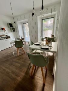 une salle à manger avec une table blanche et des chaises vertes dans l'établissement Sotto al Bosco B&B e Azienda Agricola, à Dubino