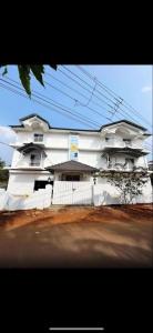 a white building with a fence in front of it at Hotel Vaibhav Hill Park in Mapusa