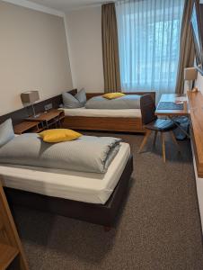 a room with two beds and a desk with a laptop at Hotel Drei Lilien in Vohenstrauß