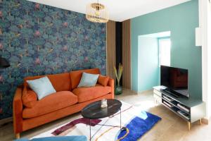 a living room with an orange couch and a tv at Les Gîtes de la Vallée du Céou in Gourdon-en-quercy