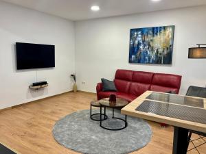 Essen的住宿－RUEHOME，客厅配有红色沙发和平面电视