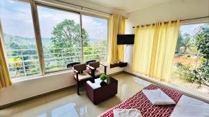a living room with a large window with a view at Elenji Vitara Resort Munnar in Munnar