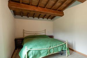 1 dormitorio con cama verde y techo de madera en La rosa del vento, en Fabbriche di Vallico