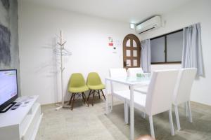 een eetkamer met een witte tafel en groene stoelen bij Tsuruhashi East III in Osaka