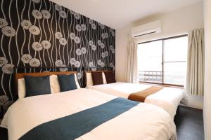 een slaapkamer met 2 bedden en een muur met bloemen bij Tsuruhashi East III in Osaka