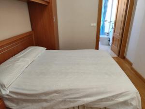 Una cama en una habitación con una sábana blanca. en Al lado de la feria en dos habitaciones Compartir con los propietarios en Albacete