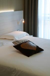 a bed with a black pillow on top of it at Foresteria La Torretta in Fino Mornasco