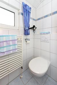 a white bathroom with a toilet and a window at Ferienwohnungen im Haus Nordseebrise in Neuharlingersiel