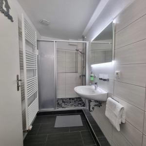 La salle de bains blanche est pourvue d'un lavabo et d'une douche. dans l'établissement Ferienwohnung in Achim Zentrum, à Achim