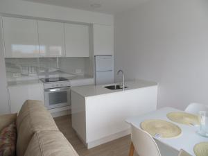 een witte keuken met een bank en een tafel bij Apartamento Centinela Do Mar in O Pindo