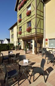 un patio avec des tables et des chaises en face d'un bâtiment dans l'établissement Als Hôtel, à Ottmarsheim