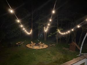 une arrière-cour avec un foyer extérieur et des lumières la nuit dans l'établissement Rustic Poconos Winding Way Chalet, à Albrightsville