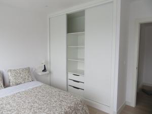 een witte slaapkamer met een bed en een kast bij Apartamento Centinela Do Mar in O Pindo