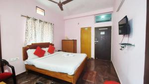 een slaapkamer met een bed met rode kussens en een televisie bij Hotel Planet 9 Puri - Wonderfull Stay with Family Near Sea Beach in Puri