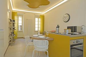 eine Küche mit einem Tisch, Stühlen und einer Uhr in der Unterkunft Gemhouse Ambra garda lake in Gargnano