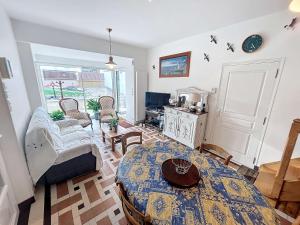 a living room with a table and some chairs at Maison à 100m de la plage, jardin privé, wifi gratuit, proche commerces et activités balnéaires - FR-1-361-113 in Jullouville-les-Pins