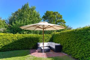 an umbrella and a couch and a chair under it at Ferienwohnungen im Haus Nordseebrise in Neuharlingersiel