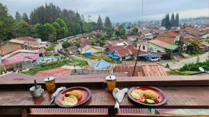 two plates of food on a table with a view of a city at RON'S Guest House Berastagi in Berastagi