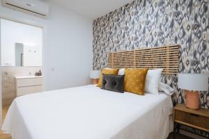 1 dormitorio con 1 cama blanca grande con almohadas en Wish Suite Miraflores de Sevilla, en Sevilla