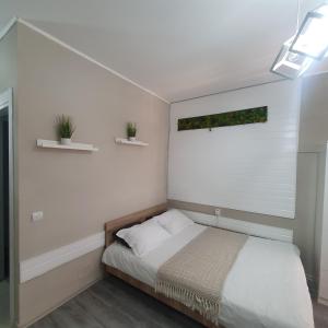 - une chambre avec un lit et deux plantes sur le mur dans l'établissement Sfanta Agnes self check in, à Popeşti-Leordeni