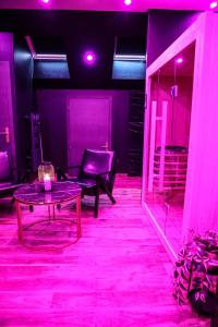 Zimmer mit einem Tisch, Stühlen und rosa Lichtern in der Unterkunft Le Premium - Suite Spa Privatif in Pontavert