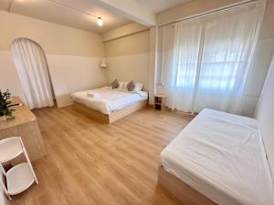 a bedroom with two beds and a desk and a window at La Moon House in Salaya