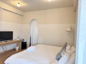a bedroom with a white bed and a television at La Moon House in Salaya