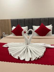 two swans in a white dress sitting on a bed at Royal Orbit in Jabalpur