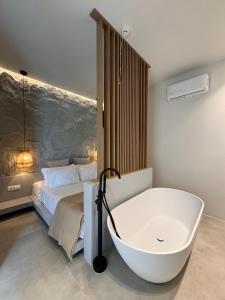 a bathroom with a bath tub next to a bed at Poema Antiparos in Antiparos