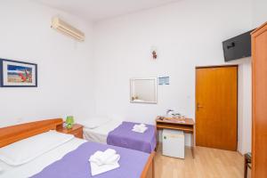 a hotel room with two beds and a desk at Rooms Olive and Sea in Tučepi