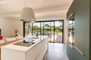 a kitchen with white cabinets and a large window at Villa Stendhal - Welkeys in Seignosse