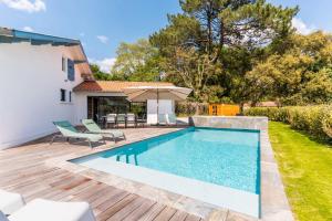 a swimming pool with chairs and an umbrella on a deck at Villa Stendhal - Welkeys in Seignosse
