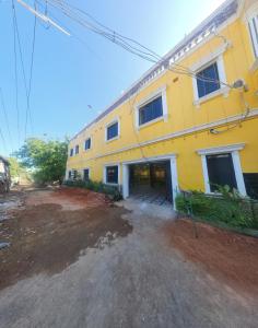 een geel gebouw met een onverharde weg ervoor bij Paradise Golden Residency in Kottakupam