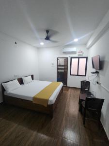 a bedroom with a bed and a table and a chair at Paradise Golden Residency in Kottakupam