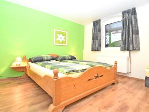 a bedroom with a wooden bed with green walls at Holiday home in ldernTwistetal Oberwaro with sauna in Oberwaroldern