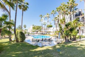 una piscina con sillas y palmeras en un parque en Jardines de las Golondrinas, en Marbella