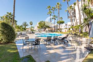 un patio con mesas y sillas junto a una piscina en Jardines de las Golondrinas, en Marbella