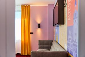 a living room with a couch and a yellow curtain at McDreams Hotel Leipzig in Leipzig