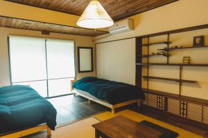 a bedroom with a bed and a table and a window at Masukichi 古民家宿ますきち 駐車場無料 in Seto