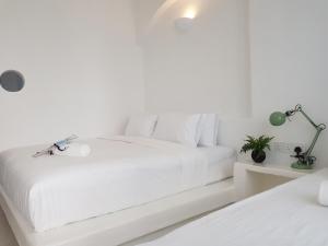 um quarto branco com uma cama grande e lençóis brancos em Ipoh Santorini Hideaway - Hotel Inspired em Ipoh